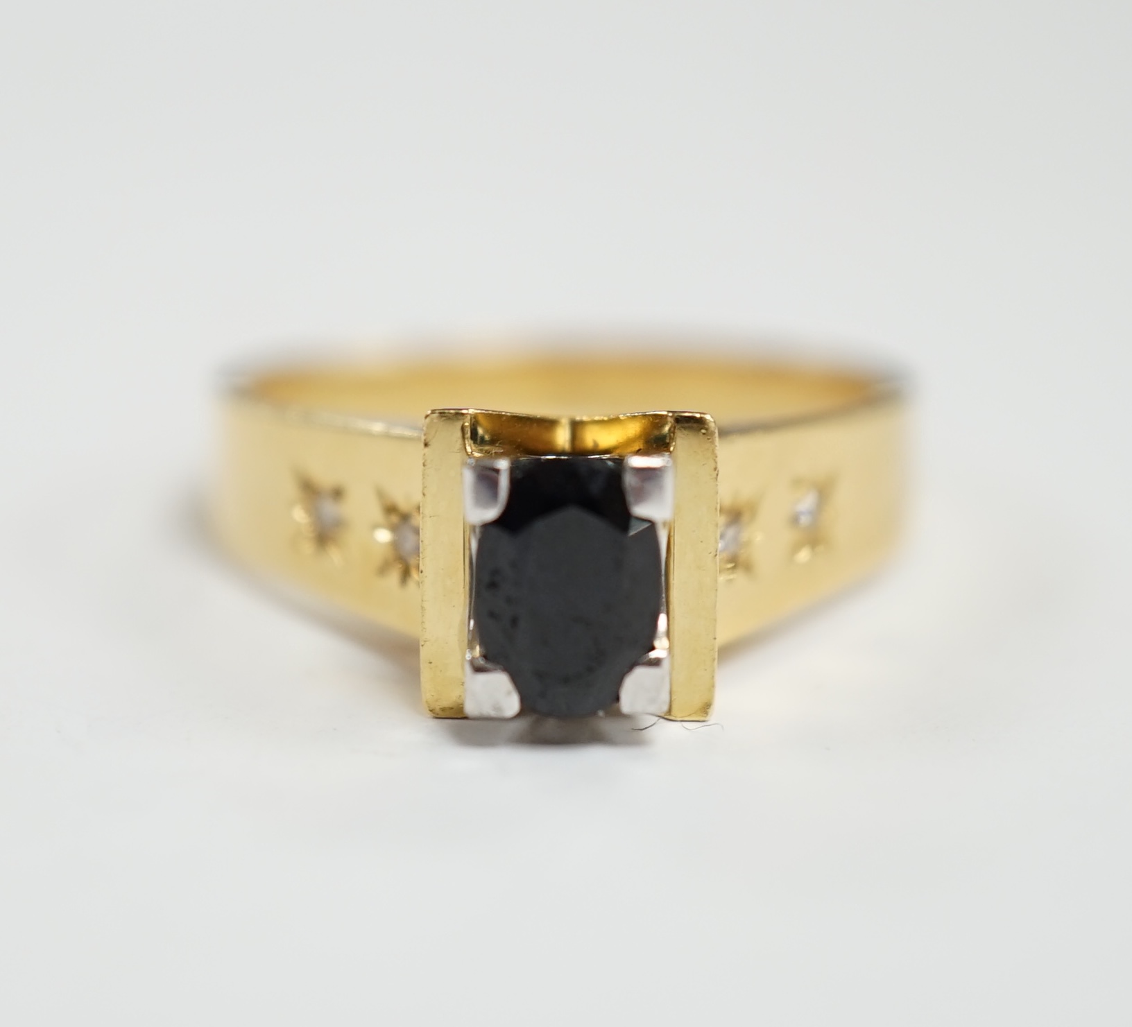 An 18ct and single stone oval cut sapphire set dress ring, with four stone gypsy set diamond chip shoulders, size R, gross weight 7.2 grams.